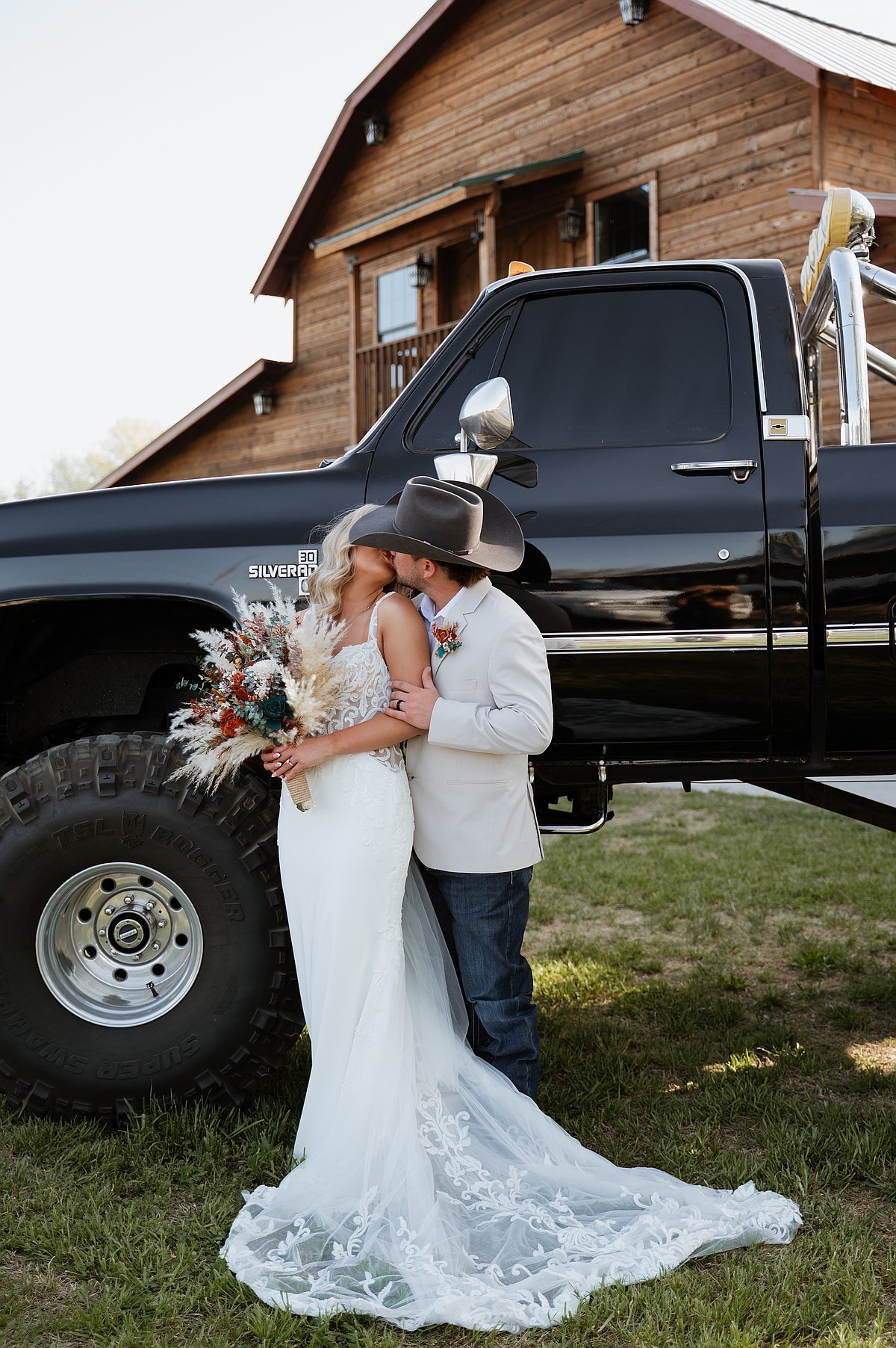 Couple kissing by vintage truck with barn in background rustic Texas wedding