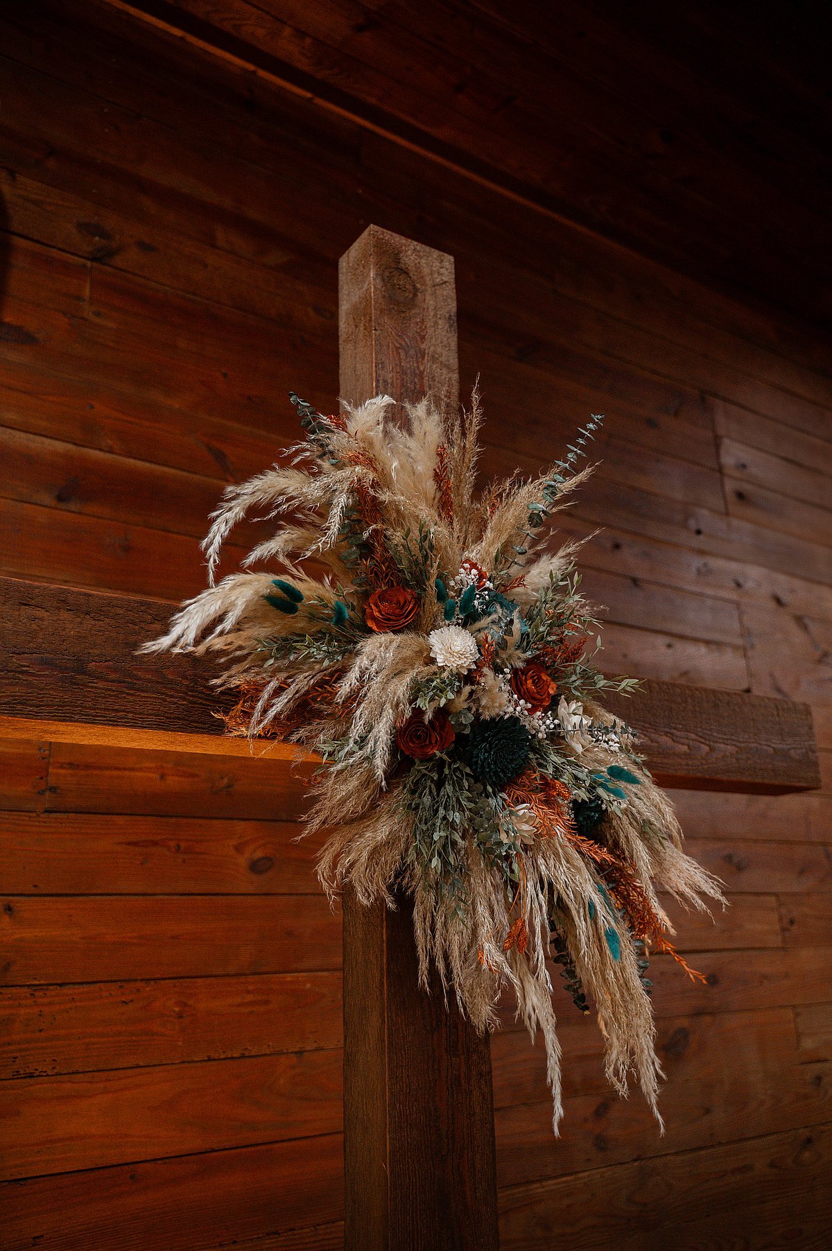 Beautiful pampas grass and floral arrangement on wooden cross close-up