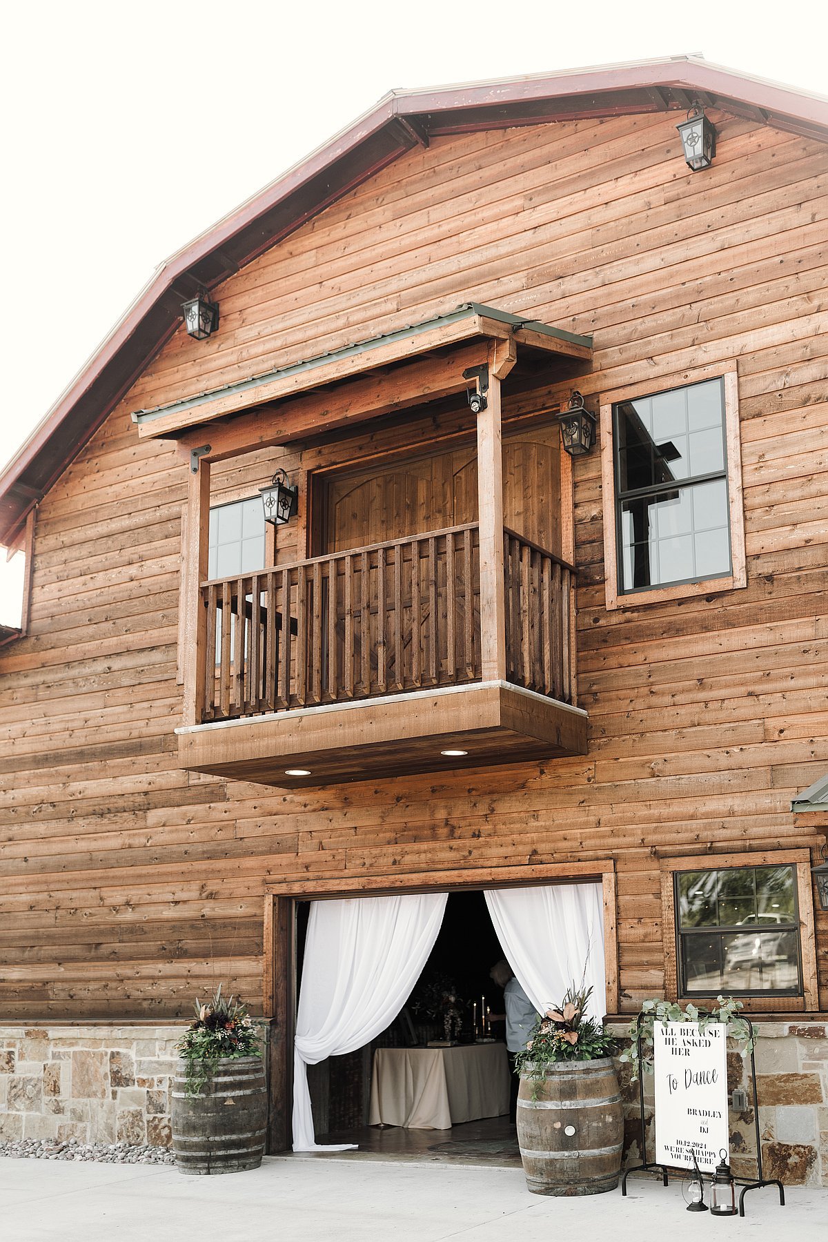 Beautiful rustic barn exterior with wooden siding balcony and white drape entrance
